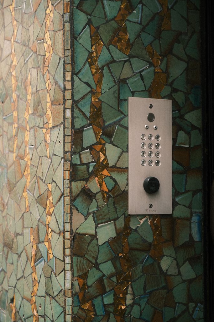 Anasayfa Close-up of a modern intercom on a decorative mosaic wall in an urban setting.